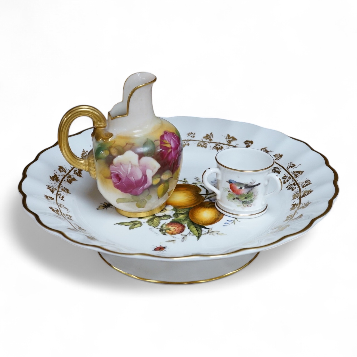 Three pieces of Worcester comprising a fruit printed and painted dish, bears signature Freeman, floral jug and a miniature tyg hand painted with a bird, largest 24cm in diameter